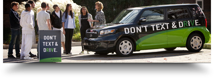 People participating in a Don't Text & Drive awareness activity beside the campaign vehicle